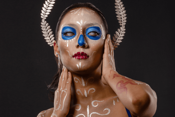 Frau mit Sugar Skull Makeup mit blauen Augen und weißen Verzierungen von Alexander Ojodelince